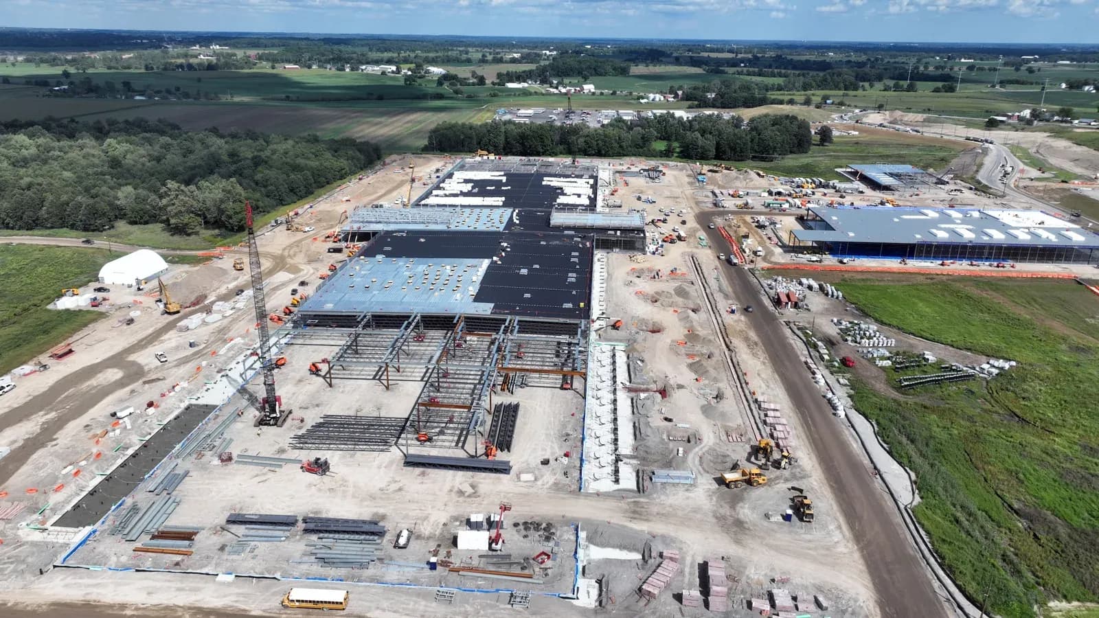 Aerial view of a large data center campus under construction, with steel-framed halls, cranes and heavy equipment