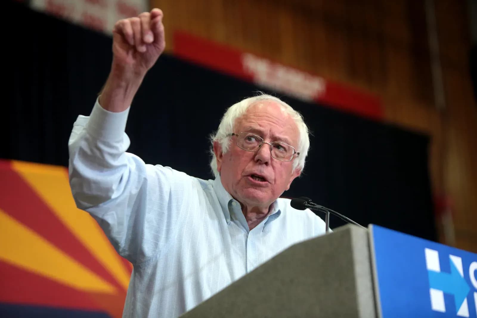Senator Bernie Sanders speaks at a podium with his fist raised during an event.